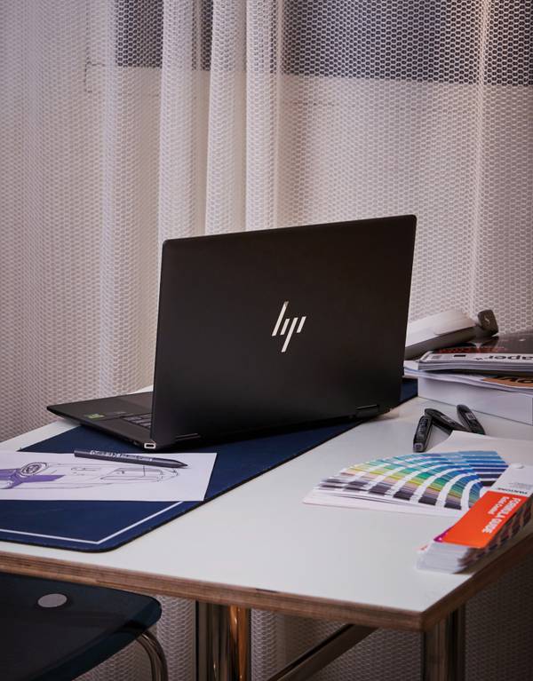디자인 작업 공간에 놓인 HP 스펙터 x360 노트북과 색상 팔레트, 스케치 자료 등의 크리에이티브 도구